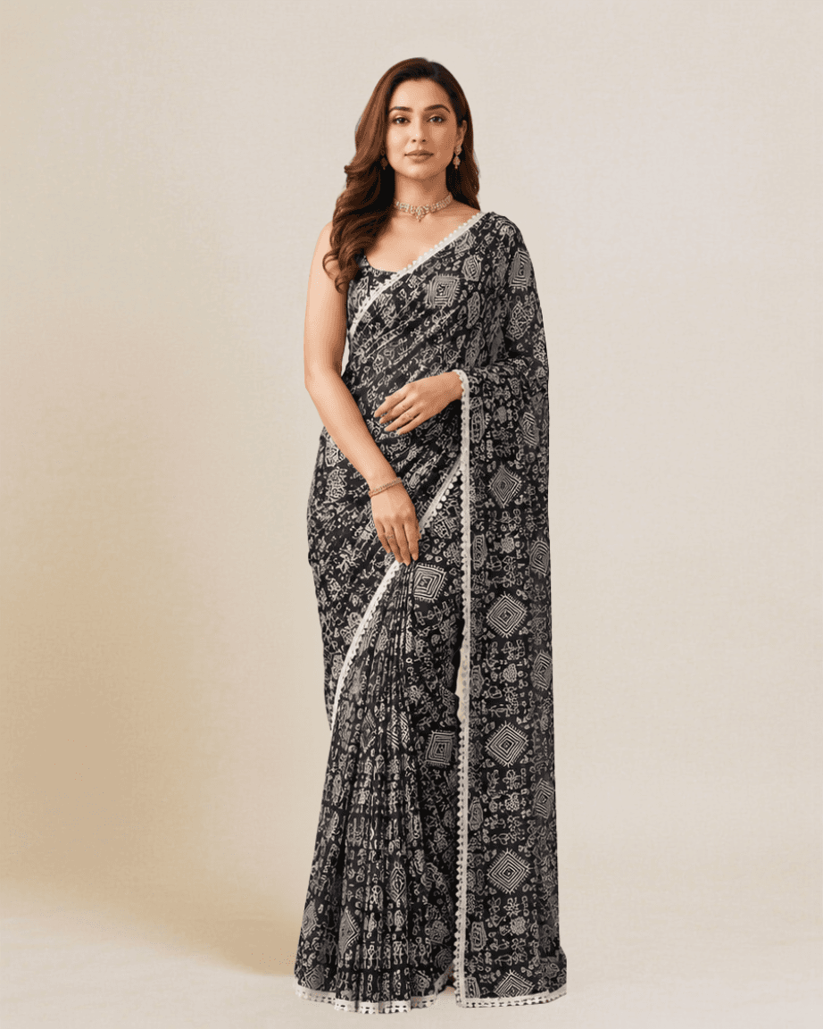 Model wearing a jet-black georgette saree with ivory Warli folk-art print and a scalloped lace border, front view